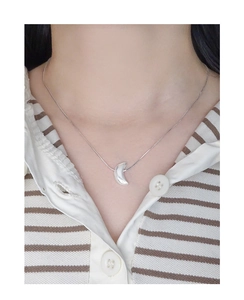 Silver crescent moon pendant on a thin snake chain shown on a model neck