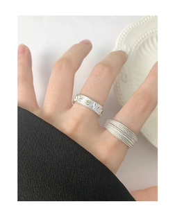Close-up of S925 silver butterfly engraved ring and layered braided band on hand