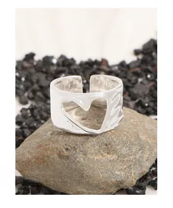 Macro shot of silver irregular hammered heart ring on rough grey stone background