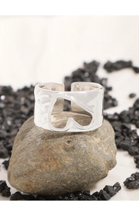 Macro detail of silver S925 irregular hollow heart ring on natural grey stone