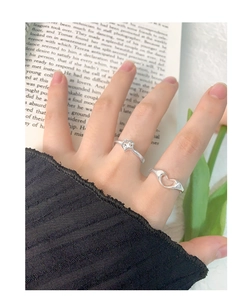 Detailed view of silver open rings with hollow heart and star designs on hand