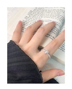 Detail of silver S925 star-shaped ring on index finger with a vintage book background