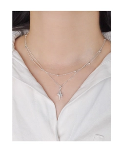 Détail d'un collier argenté à double rang avec pendentif étoile porté sur le cou