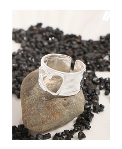 Macro shot of silver S925 heart ring with hammered texture on natural stone surface