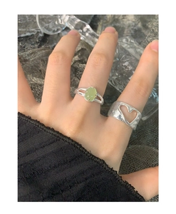 Close-up of S925 silver irregular hollow heart ring layered with green gemstone ring