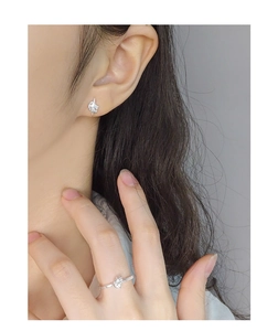 Detail of elegant silver cross star earrings and ring set on model in cool lighting