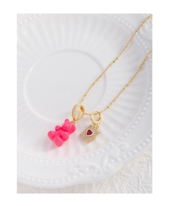 Detail of gold beaded necklace with pink gummy bear and heart zircon rectangle pendant