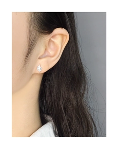 Close-up of minimalist silver star stud earring worn on ear with polished finish