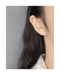 Detailed close-up of a silver starburst stud earring worn by a model in soft light