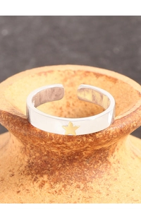 Macro shot of S925 silver open ring with a gold star detail on ceramic vessel
