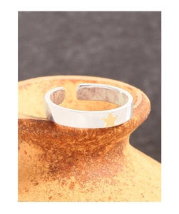 Macro shot of silver S925 star ring with gold contrast star on rustic ceramic edge
