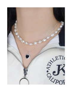 Double-layer necklace with baroque pearls, silver chain, and black heart pendant on a model