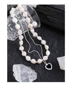 Detailed close-up of double-layer necklace with irregular pearls and black heart pendant