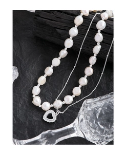 Detailed macro of baroque pearl layered necklace with hollow heart silver pendant