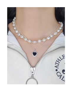 Close-up of double-layer necklace featuring baroque pearls and black heart pendant