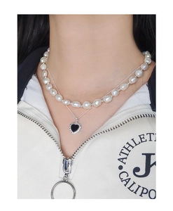 Close-up of double-layer necklace with irregular pearls and black heart pendant on model