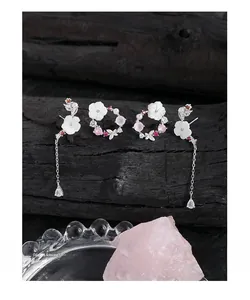 Detailed view of silver flower earrings with shell petals and pink zircon tassels