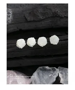 Gros plan de boucles d'oreilles roses en nacre sur bois noir avec cristaux de quartz