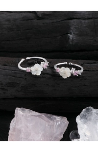 Macro detail of S925 silver flower rings with white shell petals and pink zircon accents