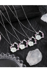 Détail de colliers avec pendentif fleur en nacre, zircon rose et chaînes en argent