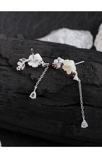 Macro shot of asymmetric flower earrings with shell petals and long pear-shaped crystal drops