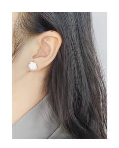 Gros plan de boucles d'oreilles roses blanches portées, montrant une texture mate