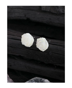 Gros plan sur des boucles d'oreilles rose en nacre blanche sur fond texturé noir