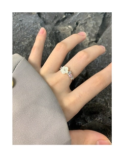 Close-up of S925 silver flower ring with natural shell petals and pink zircon accents