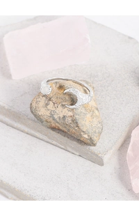 Detailed view of S925 silver moon ring with white opal on a textured stone base