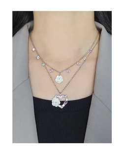 Close-up of double-layered silver necklace featuring shell flower and zircon heart pendants