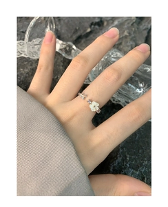 Détail d'une bague ouverte en argent S925 avec fleur en nacre et papillon au doigt