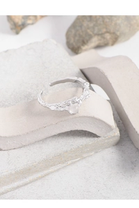 Macro detail of irregular lava texture silver ring with round translucent gemstone