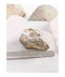 Macro shot of silver textured moon ring with opal stone on a natural grey rock