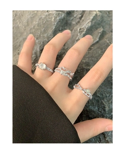 Detailed view of silver stackable rings with irregular texture and light cyan gemstones
