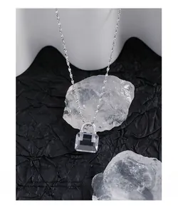 Macro detail of S925 silver necklace with crystal mini bag pendant on textured background