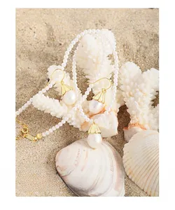 Detail of S925 silver pearl necklace and drop earrings set on a beach sand background
