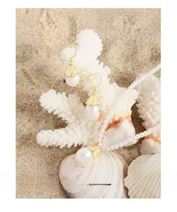 Close-up of pearl wind chime flower earrings and necklace on a sandy beach setting