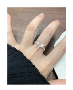 Close-up of a silver butterfly wing ring worn on finger over a wooden background