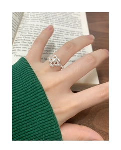 Detail of S925 silver flower ring with pearl inlay worn on hand over a book