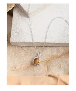 Close-up of oval tiger eye stone pendant on S925 silver chain over autumn leaves