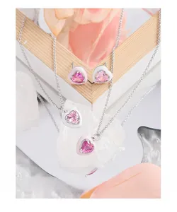 Pink heart-shaped necklace and earrings set with zircons on a crystal and orchid background