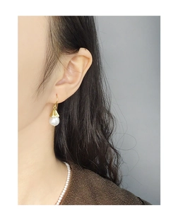 Detail view of S925 silver bellflower pearl earrings on model with golden hooks