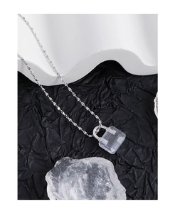 Detailed macro view of a square-cut clear crystal pendant on a thin silver chain necklace