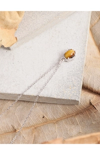 Detail of oval tiger eye stone pendant with S925 sterling silver chain on a stone surface