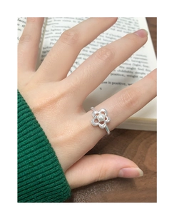 Close-up of S925 silver flower ring with white pearl on a vintage open book background