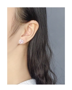 Close-up of a model wearing a sweet S925 silver heart stud earring with pink zircon