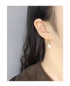Detail shot of a vintage bellflower pearl earring worn elegantly by a model