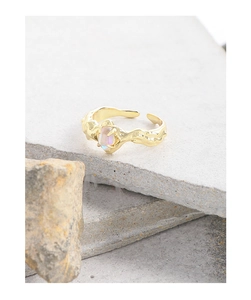 Macro detail of gold irregular lava texture ring with glowing iridescent moonstone
