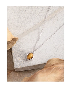 Detailed view of an oval tiger eye stone pendant on a silver S925 chain over stone
