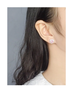 Close-up of a model wearing a delicate pink heart-shaped zircon stud earring in S925 silver